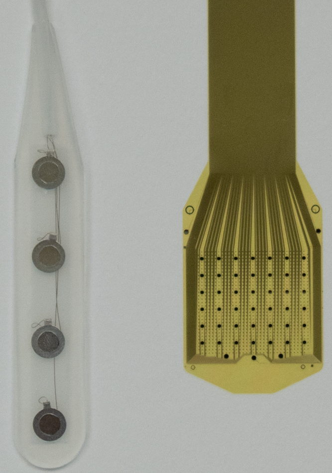 Photograph comparing a conventional four-contact ECoG strip on the left with the densely patterned Precision Layer 7 cortical array on the right.
