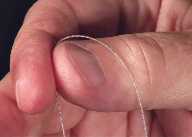 Very fine coiled MicroLead 2.0 wire draped around a person's fingertip and thumb.